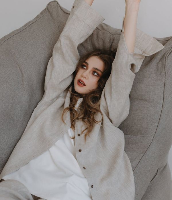 Woman in a light-filled room, stretching gracefully and feeling energized.